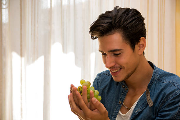 istock Young man holding a ripe bunch of grapes 527169203