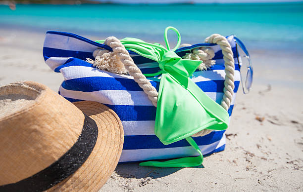 istock Stripe bag, straw hat, sunblock and frisbee on white beach 527171653