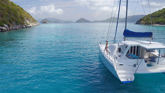 Woman relaxing on a beatiful Catamaran anchored in clear tropical water in the Caribbean