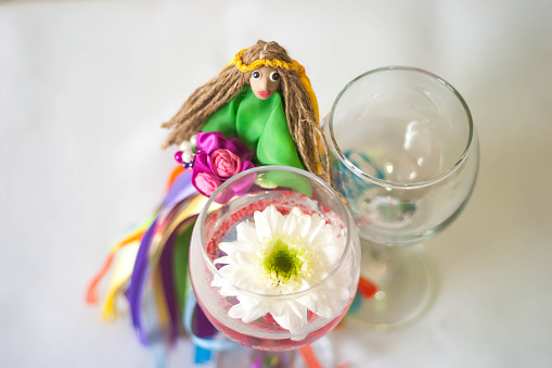 Decor for the tabletop flower arrangement. Doll in a green dress with multi-colored ribbons and bouquet in her hands and wearing a crown of yellow ribbons