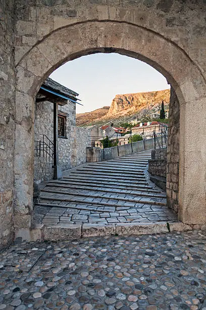 View to the Old Bridge of Mostar (Bosnia and Herzegovina) through the entrance gate. The bridge was destroyed during the Croat-Bosniak War in September 1993 and was reconstructed after the war in 2004. The bridge crosses the river Neretva and is a part of the Old Town of Mostar that was declared as an UNESCO World Heritage site in 2005.