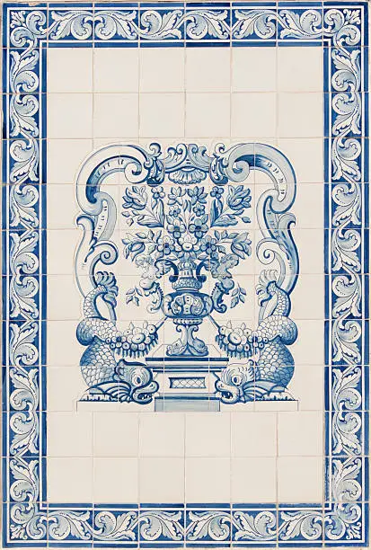 Colorful antique tiles or azulejos in the Algarve in Portugal with a decoration of a vase with flowers and some fish.