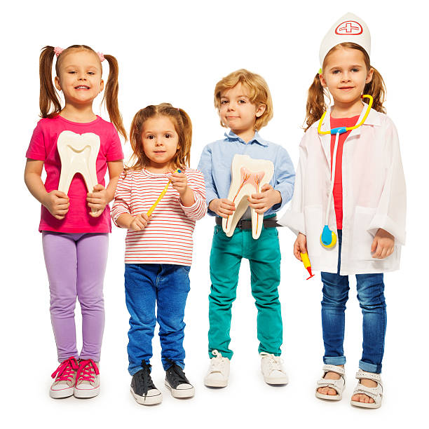 Four little children playing doctors Four little children playing doctors with teeth dummies, toothbrush and stethoscope, isolated on white background pediatric dentistry stock pictures, royalty-free photos & images