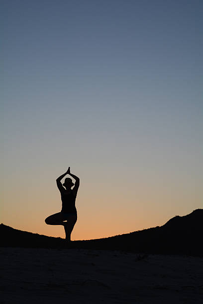 Woman in a Yoga Tree Pose after Sunset stock photo