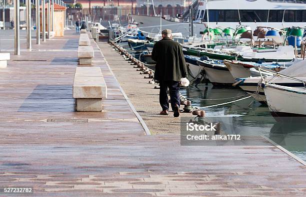 Older Man Walks Along Attached Boats Stock Photo - Download Image Now - Adult, Aging Process, Autumn