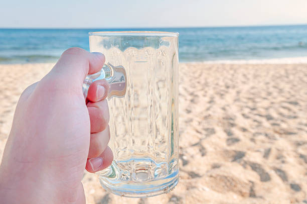 istock Empty mug of drained fresh beer on the beach 527236432