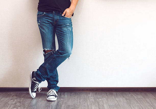 Man's legs Young fashion man's legs in jeans and sneakers on wooden floor jeans stock pictures, royalty-free photos & images