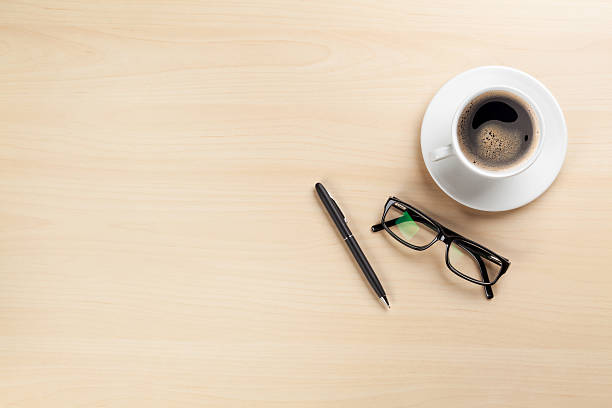 Office desk with coffee, pen and glasses
