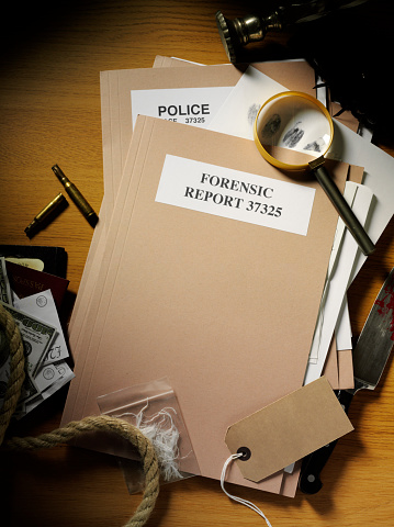 Police and forensic paperwork files, overhead view with a magnifying glass and evidence from the crime. Copy space