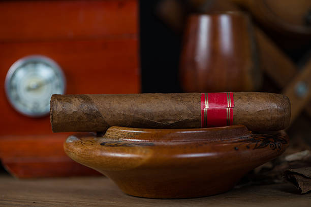 Cuban cigar in ashtray with humidor and rum barrel