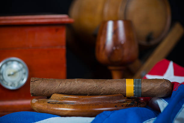 istock Cuban cigar in ashtray with humidor and rum barrel 527275365