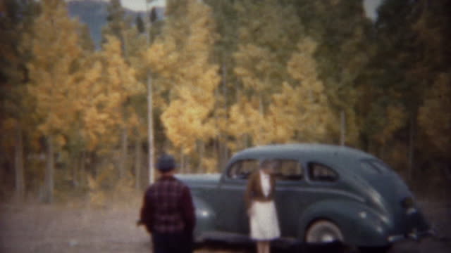 1940: Light blue sedan car parked in autumn yellow colors forest.