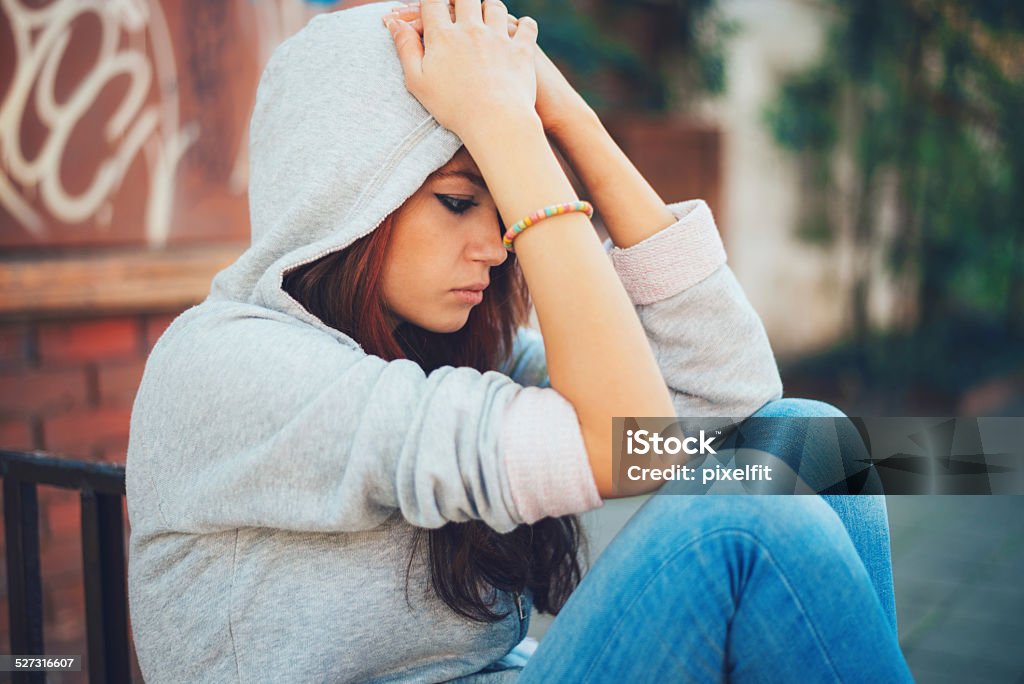 Depressed teen girl sitting lonely Lonely teenager sitting outdoors Adolescence Stock Photo