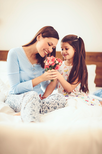 Happy mother's day. Children daughters are congratulating mom and giving her flowers. Mum and girls smiling and hugging. Family holiday and togetherness.