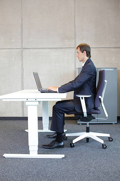 mann in anzug sitzt in der richtigen position am arbeitsplatz - ergonomische tastatur stock-fotos und bilder