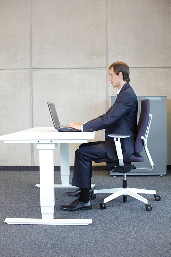 man in suit in correct sitting position at workstation in office