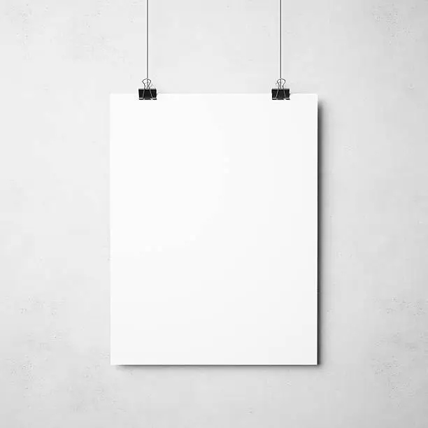 blank poster hanging on binders on concrete background