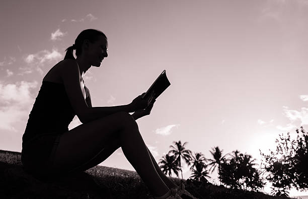 Woman reading book Silhouette of young woman reading book outdoors. stars in your eyes stock pictures, royalty-free photos & images