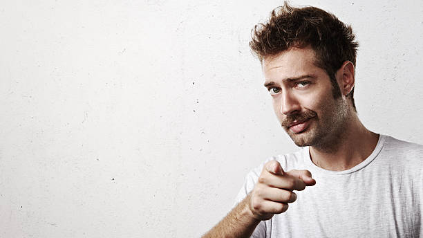 Young man pointing towards the camera Portrait of a young man pointing towards the camera moustache stock pictures, royalty-free photos & images