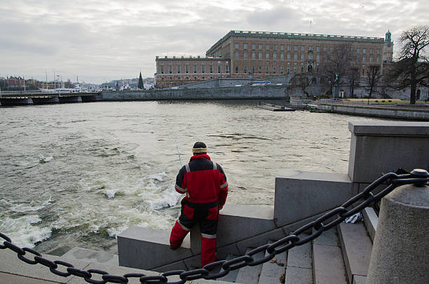 Stockholm Royal Palace in Sweden Stockholm, Sweden - November 28, 2014: The Royal Palace in Stockholm the capital of Sweden with an angling man by the streaming water. This place, in the center of Stockholm, is very popular  for angling. Photo taken on 28 November 2014 at Strommen, Stockholm, Sweden. strommen stock pictures, royalty-free photos & images