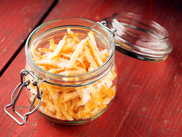 Homemade candied orange peel Homemade candied orange peel in glass container on red wooden table candied fruit stock pictures, royalty-free photos & images