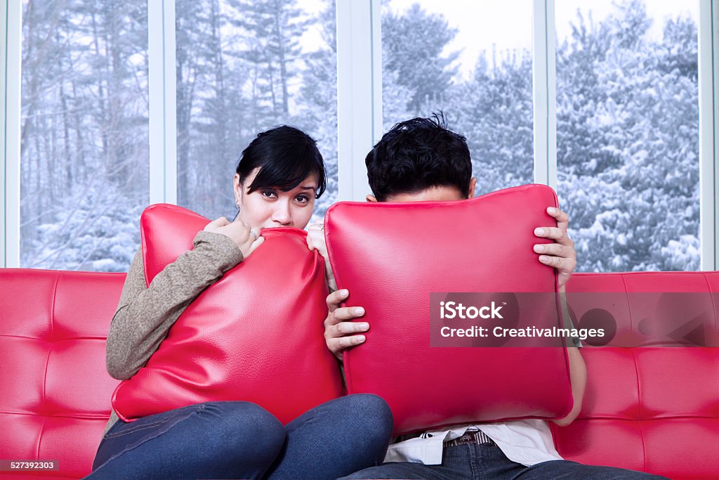 Couple hiding on the pillows Portrait of scared couple watching horror movie at home and hiding on the pillows 20-24 Years Stock Photo