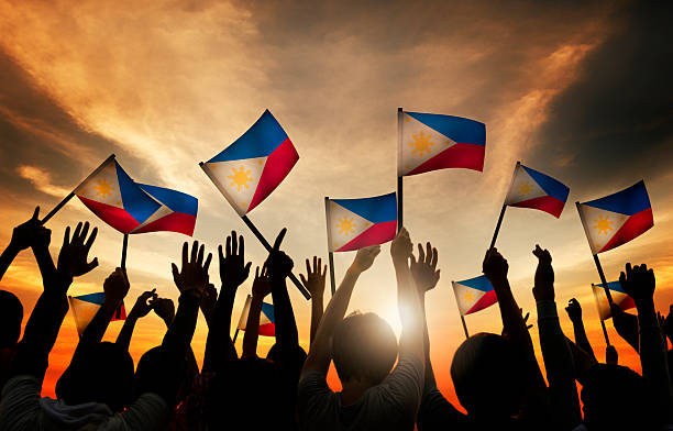 grupo de pessoas agitando bandeiras filipina em iluminação de fundo - philippino flag - fotografias e filmes do acervo