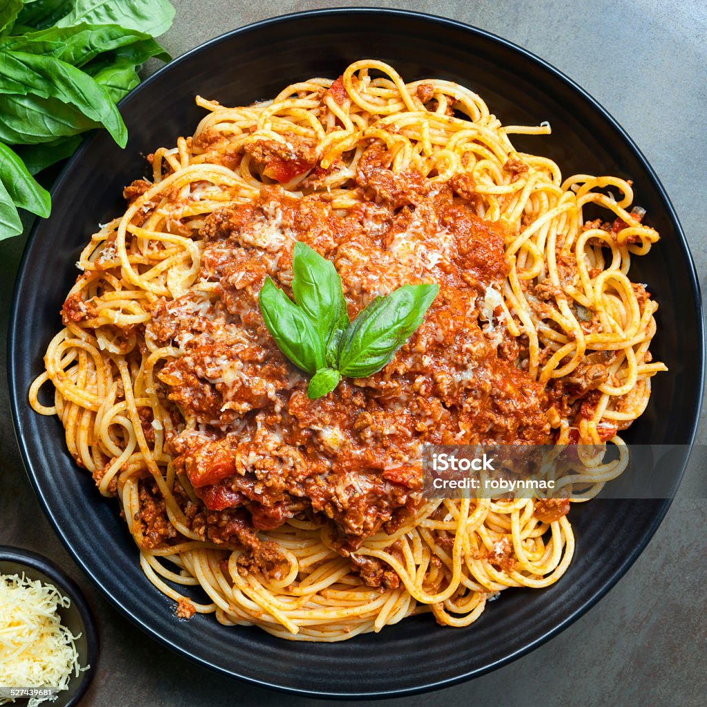 Spaghetti Bolognese Spaghetti bolognese in black serving platter, with fresh basil and parmesan. Bolognese Sauce Stock Photo