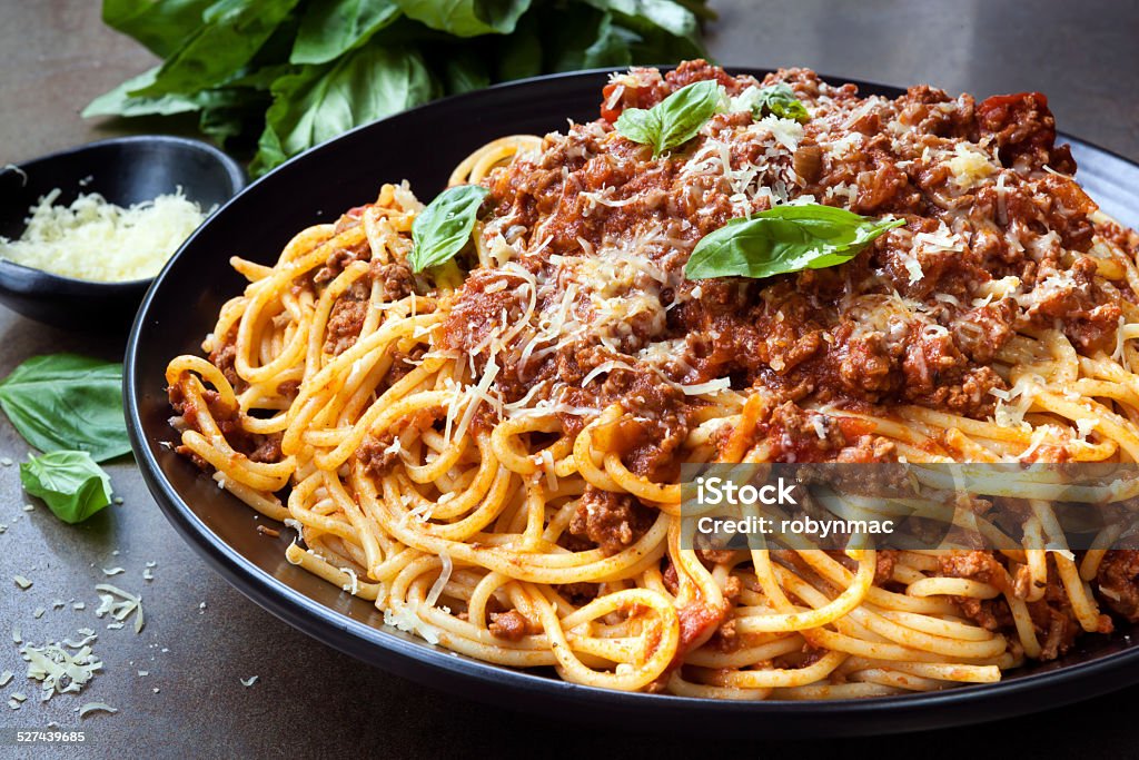 Spaghetti Bolognese Spaghetti bolognese in black serving platter, with fresh basil and parmesan. Pasta Stock Photo
