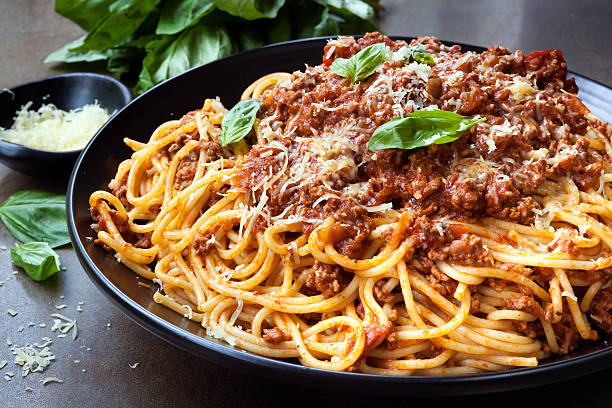 Spaghetti Bolognese Spaghetti bolognese in black serving platter, with fresh basil and parmesan. pasta stock pictures, royalty-free photos & images