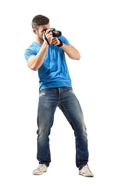 istock Standing young man taking photo with digital camera 527441327