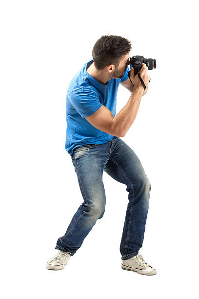 Bend young man taking photo with digital camera side view