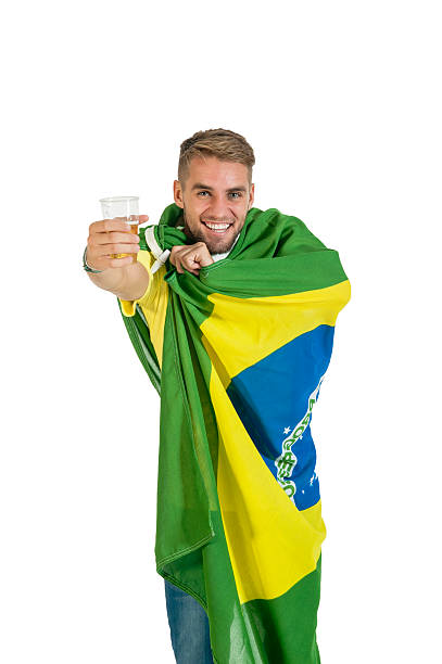 young handsome guy wrapped in brazil flag with beer stock photo