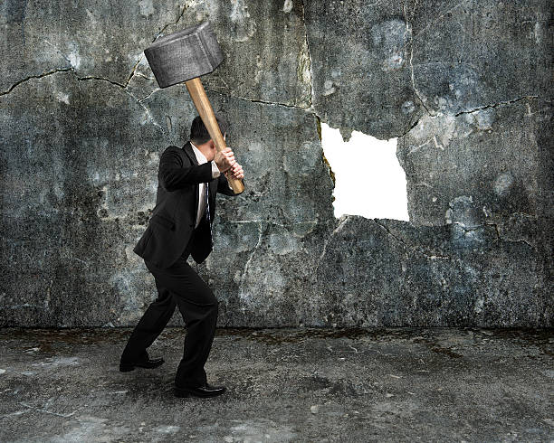 businessman hold sledgehammer cracking big white hole on concret stock photo