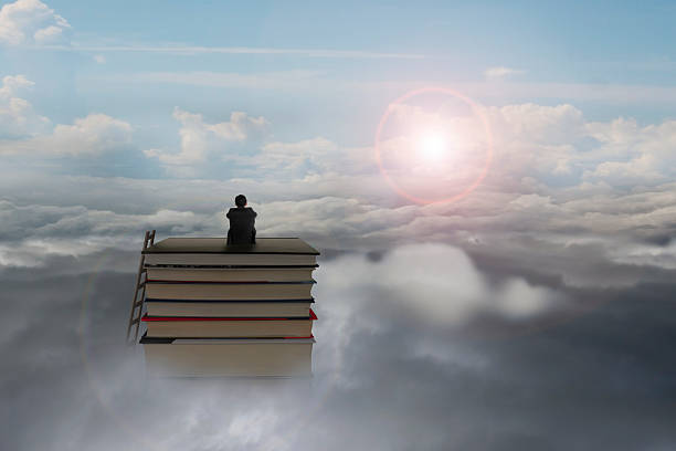 istock pondering businessman sitting on stack of books with sunlight cl 527444031