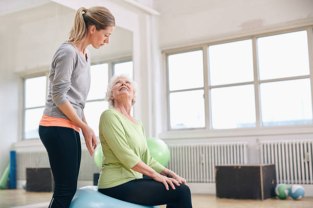 istock Female coach assisting senior woman exercising 527463441
