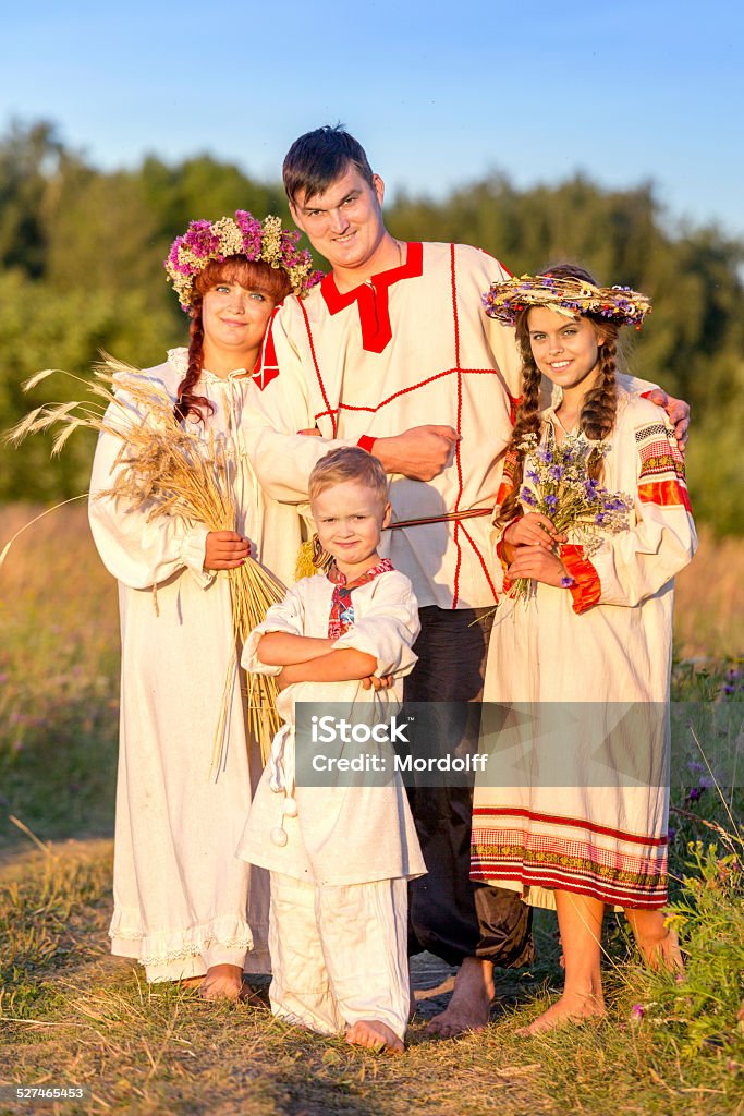 Happy Russian family Beautiful family in Russian folk costumes standing together outdoors at summer sunset Summer Solstice Stock Photo