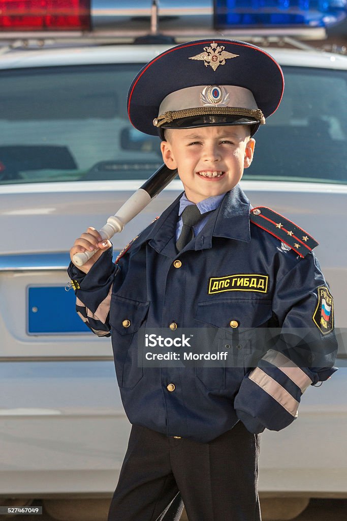 Happy little police officer Smiling little boy in police uniform next to police car outdoors Activity Stock Photo