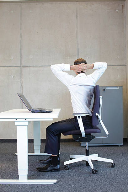 exercises in office. business  man with arms on head. exercises in office. business  man with arms on head  sitting on office armchair at the desk - back view ergonomic keyboard photos stock pictures, royalty-free photos & images