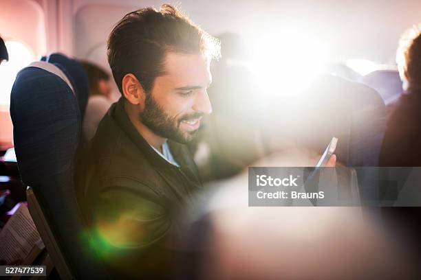 Young Man Using Smart Phone In Airplane Stock Photo - Download Image Now - Adult, Air Vehicle, Airplane