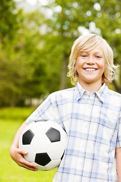 istock Happy boy playing with a football while outdoors 527478371