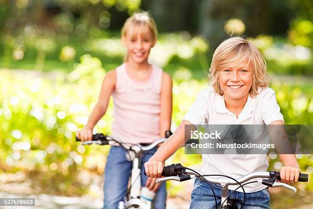 Glücklich Junge Fahrradfahren Mit Schwester Hinten Im Park Stockfoto und mehr Bilder von Kind