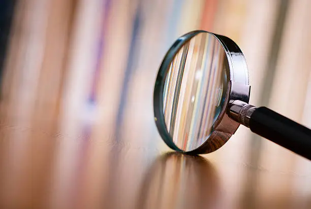 Close up Single Magnifying Glass with Black Handle, Leaning on the Wooden Table at the Office.