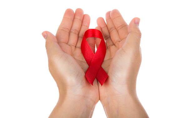 istock AIDS ribbon in hand isolated on white background 527480237