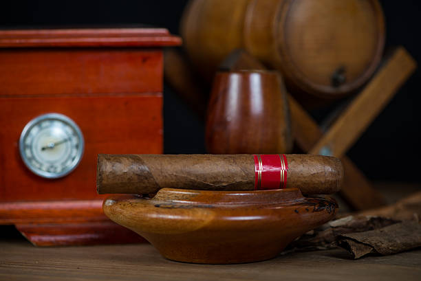 istock Cuban cigar in ashtray with humidor and rum barrel 527491195