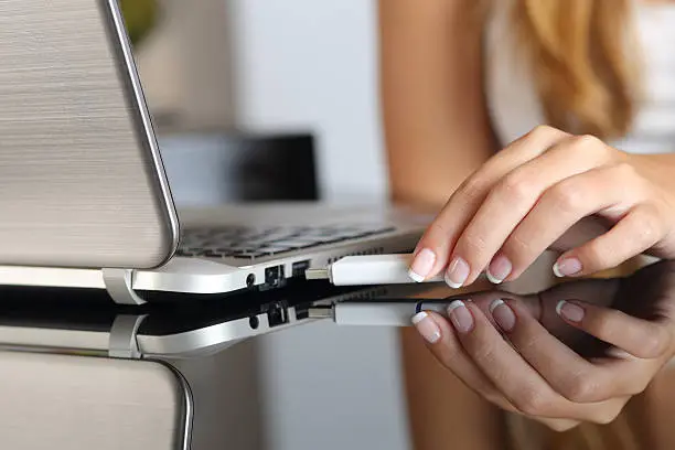 Photo of Woman hand plugging a pendrive on a laptop at home