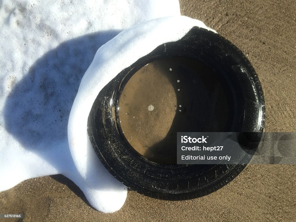 Tire washed up on beach Aguada, Puerto Rico - November 19, 2014: A washed up tire rests on the beach as waves crash over it. Pollution Stock Photo