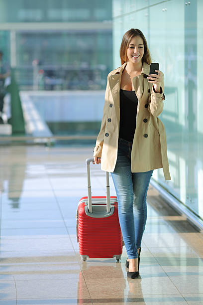mulher andar e usando um telefone inteligente em um aeroporto - business travel people traveling airport journey imagens e fotografias de stock