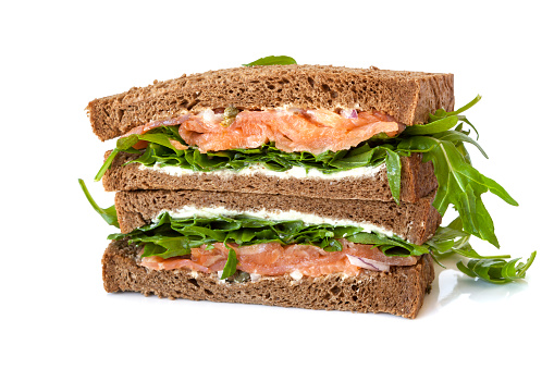 Smoked salmon sandwich on rye with arugula, cream cheese and capers.  Isolated.Smoked salmon sandwich on rye with arugula, cream cheese and capers.  Isolated.