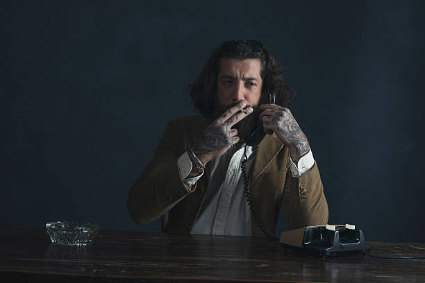 istock Retro 1970 undercover agent with beard calling behind desk. 527521330